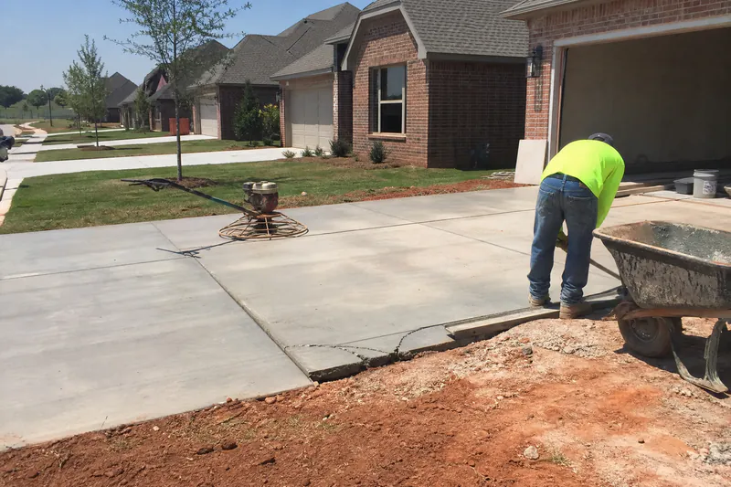 Builder-grade concrete driveway with early corner cracks in a new Mustang, Oklahoma subdivision