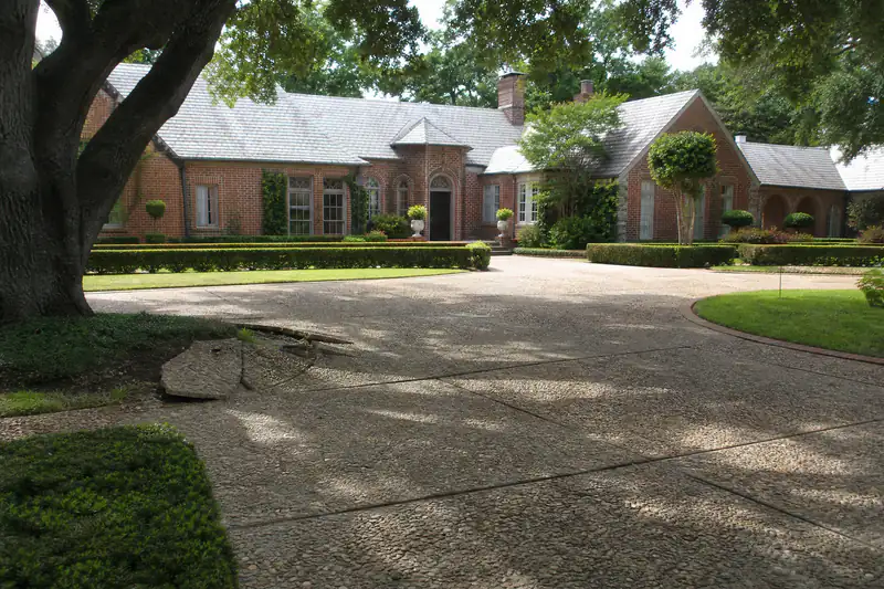 Long circular exposed-aggregate driveway under a mature tree canopy at an estate home in Nichols Hills, Oklahoma