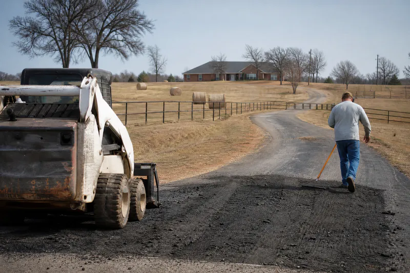 Long asphalt driveway crossing a pasture on an acreage property in Piedmont, Oklahoma
