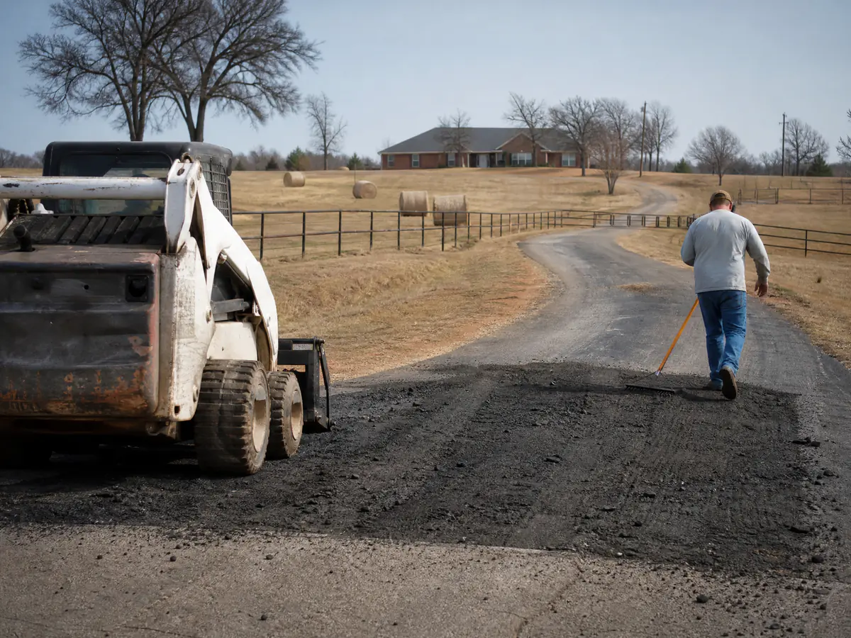Long asphalt driveway crossing a pasture on an acreage property in Piedmont, Oklahoma