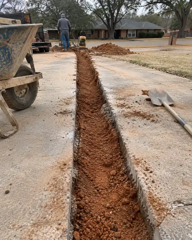 Utility trench cut across a concrete driveway awaiting repair in Oklahoma City